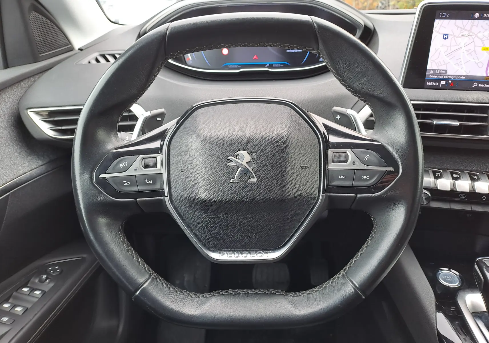 Vue rapprochée du volant en cuir noir du Peugeot 3008 2018 avec commandes intégrées et tableau de bord digital.