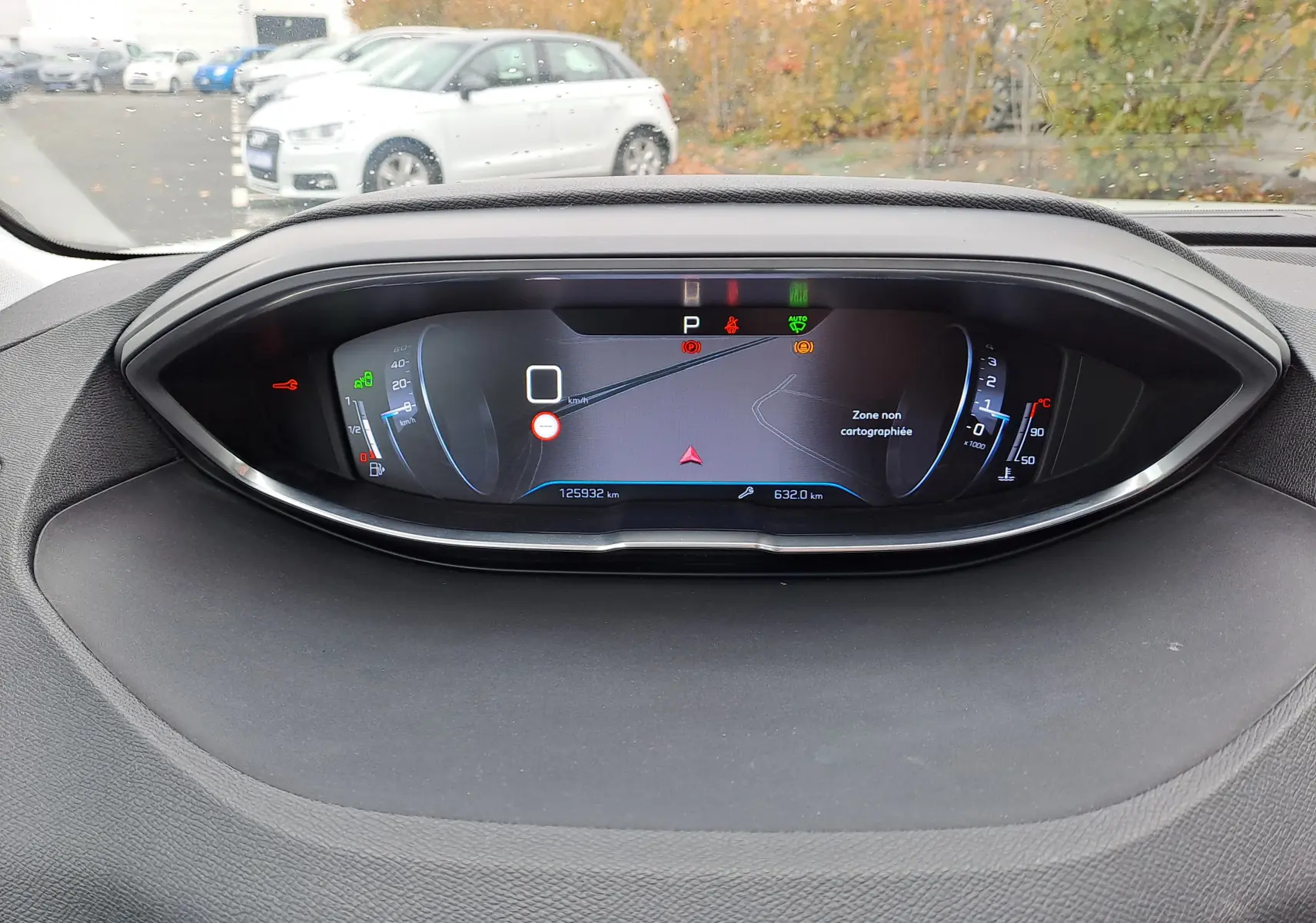 Tableau de bord numérique du Peugeot 3008 blanc, affichant la vitesse à zéro et la navigation sur zone non cartographiée.