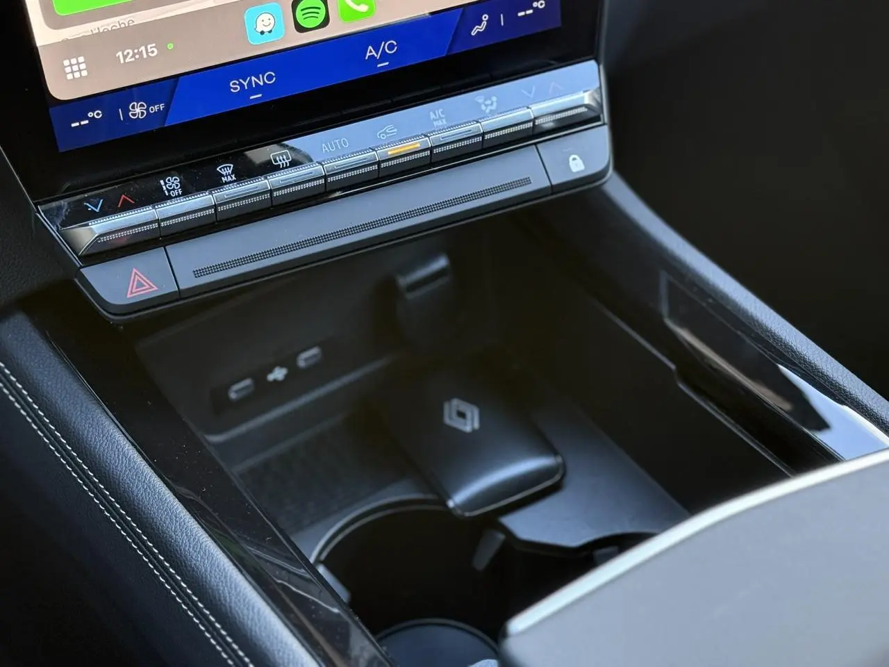 Gros plan sur la console centrale noire du Renault Espace VI avec commandes climatisation et chargeur sans fil visible