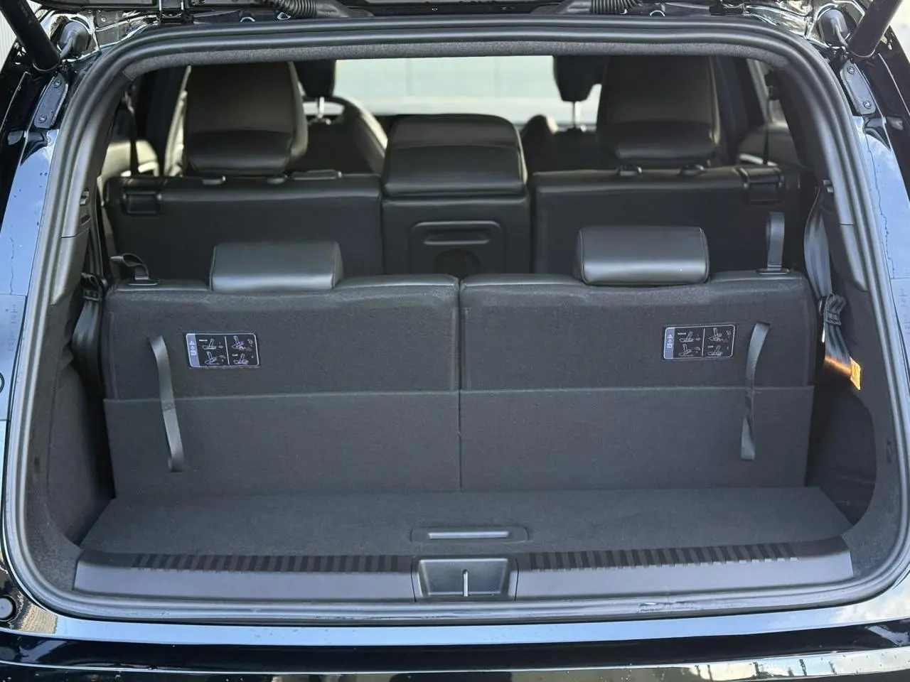 Coffre ouvert du Renault Espace noir étoilé, vue arrière montrant la banquette arrière en position haute.