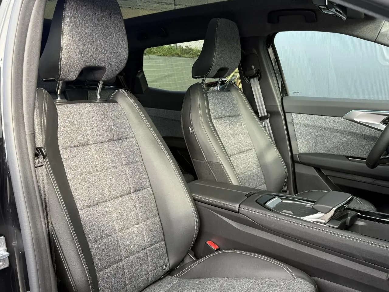 Vue intérieure côté conducteur du Renault Espace VI 6 E-Tech avec sièges tissu gris et cuir noir, accoudoir central visible.