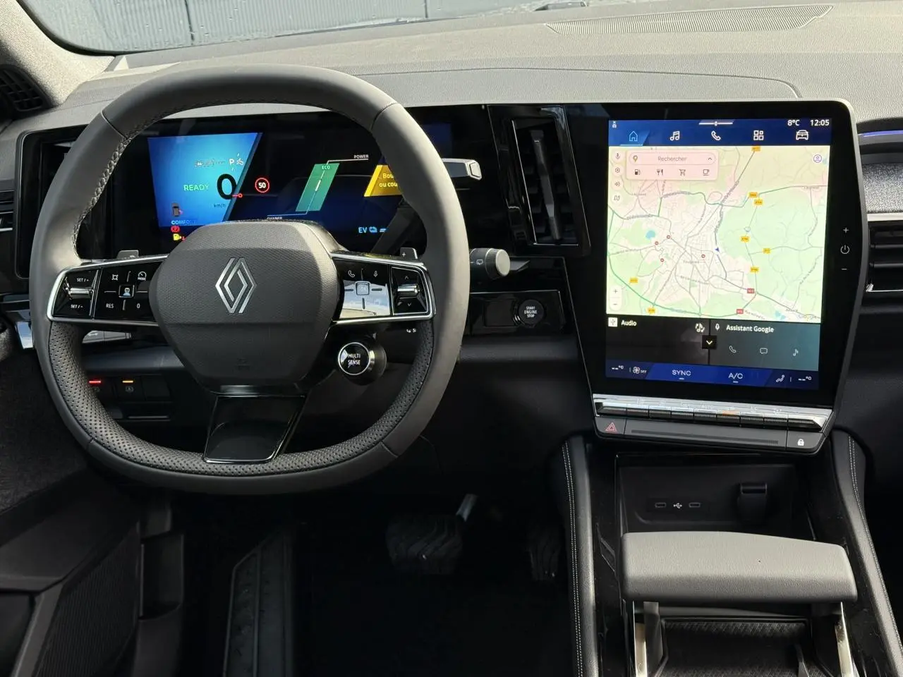 Intérieur Renault Espace 2025, vue du poste de conduite avec volant multifonction et grand écran tactile central affichant la navigation.