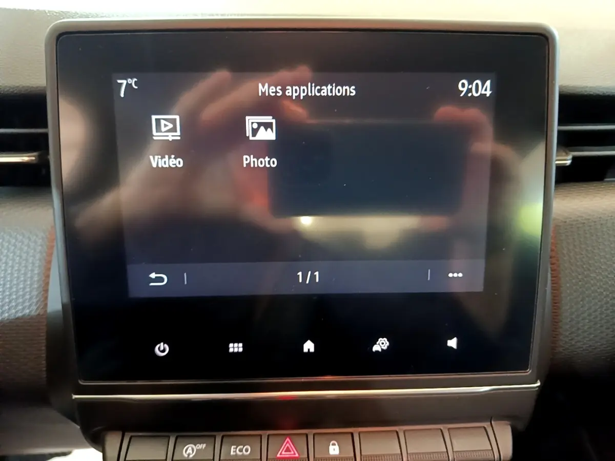 Écran tactile central affichant les applications vidéo et photo dans l'habitacle d'une Renault Clio Business blanche.