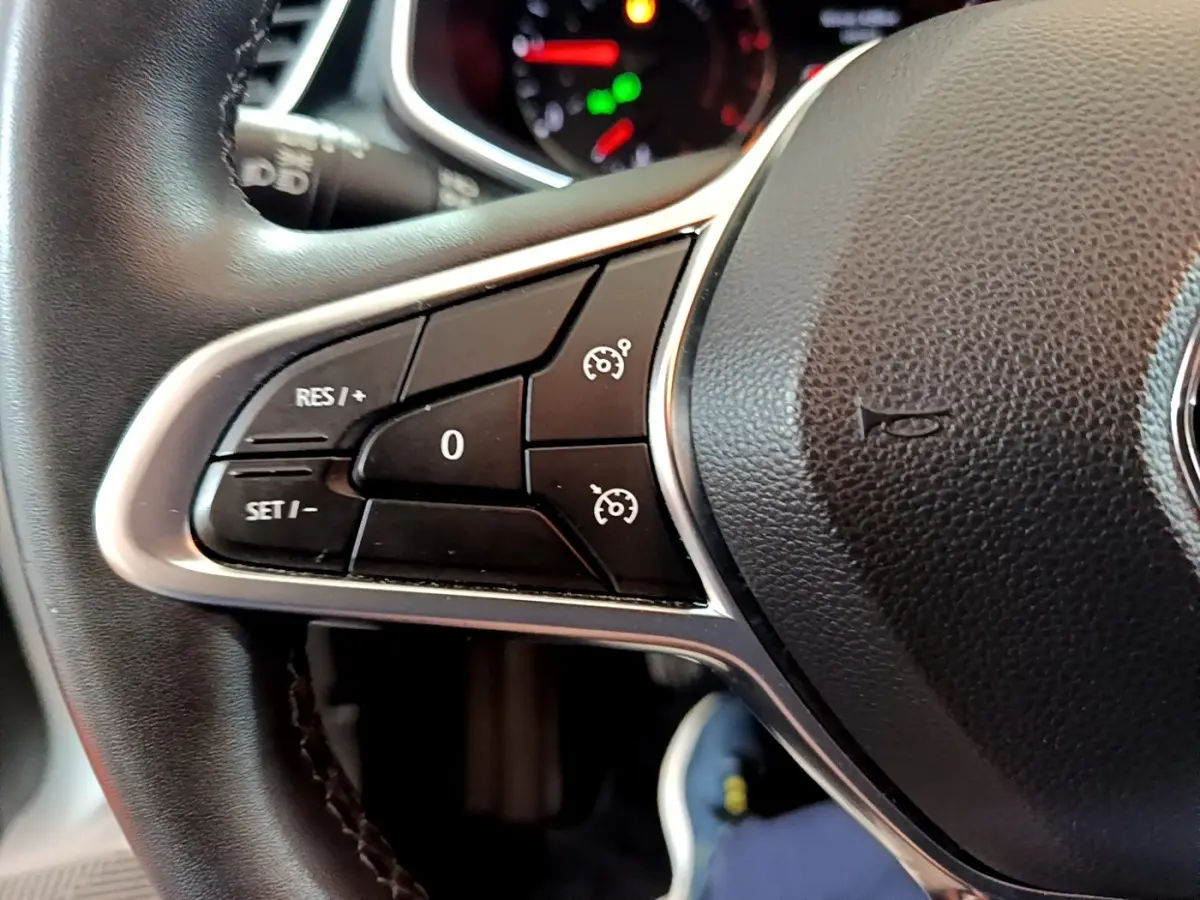 Gros plan sur les commandes du régulateur de vitesse au volant cuir noir de la Renault Clio Business Blue dCi 2020.