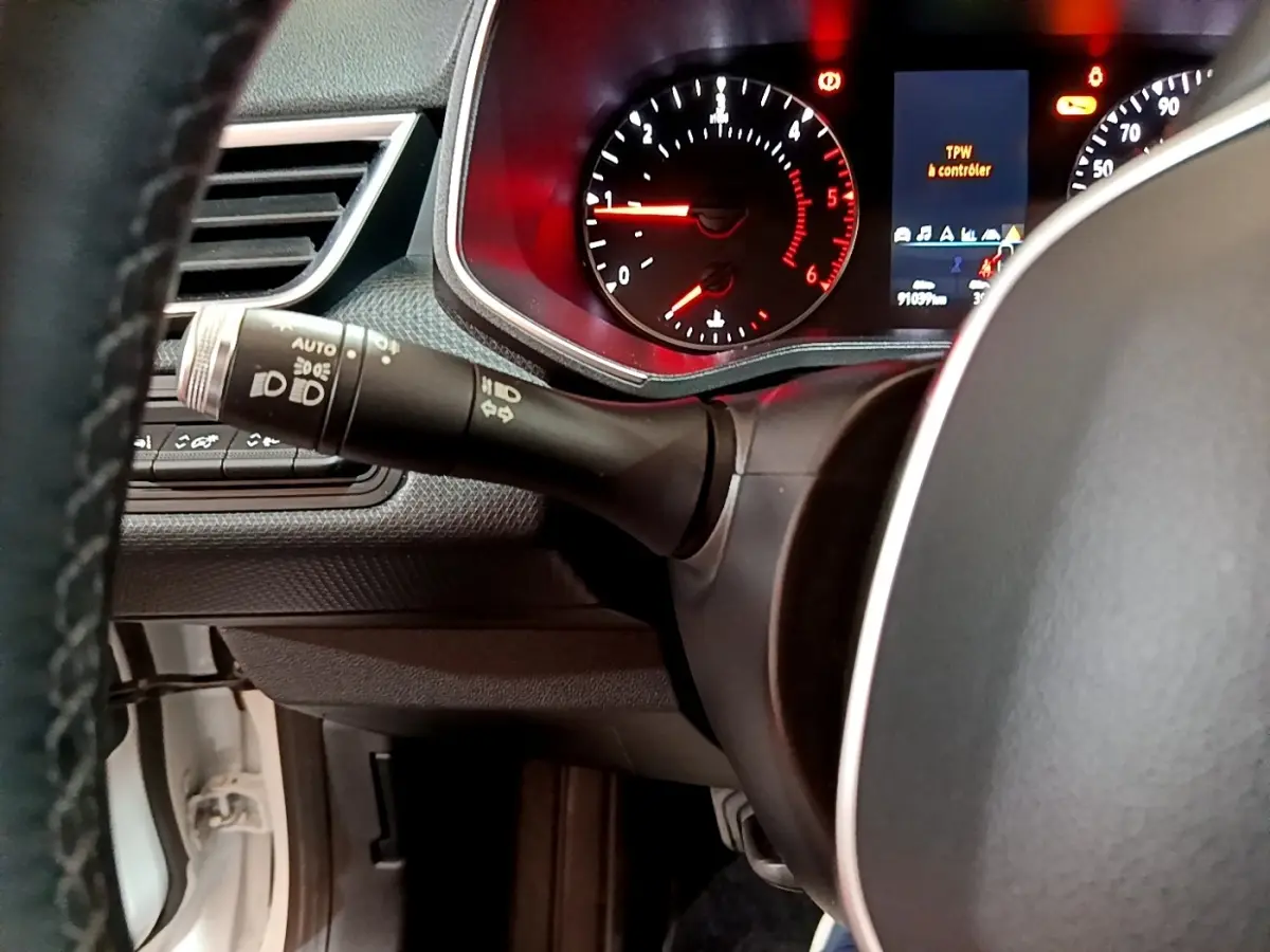 Gros plan sur le tableau de bord et le volant de la Renault Clio Business Blue dCi 85 blanc, avec affichage digital et commandes au volant.