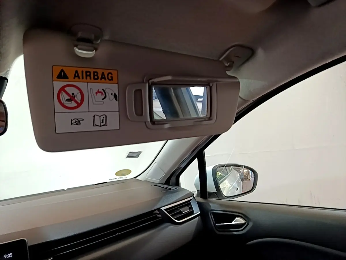 Détail intérieur côté passager de la Renault Clio blanche 2020, avec pare-soleil ouvert et miroir visible.