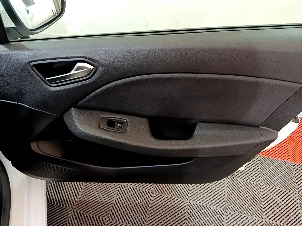 Gros plan sur la porte intérieure côté gauche d'une Renault Clio Business blanche, avec poignée argentée et bouton de vitre électrique.