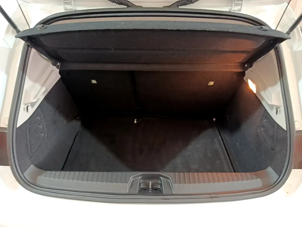 Coffre ouvert vu de face d'une Renault Clio Business Blue dCi 85 blanche, intérieur noir et éclairage latéral.