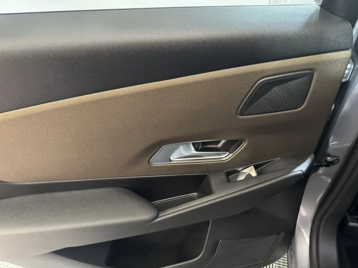 Vue intérieure côté droit de la porte arrière gris foncé du DS7 Crossback avec poignée argentée et haut-parleur intégré.