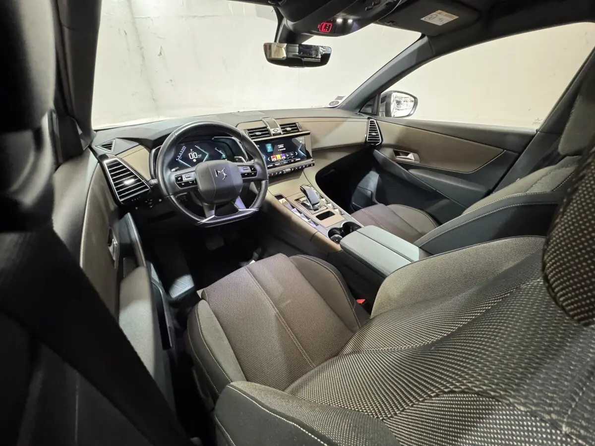 Vue intérieure avant droite du DS7 Crossback E-TENSE 225 Bastille+ montrant le tableau de bord et les sièges en tissu gris.