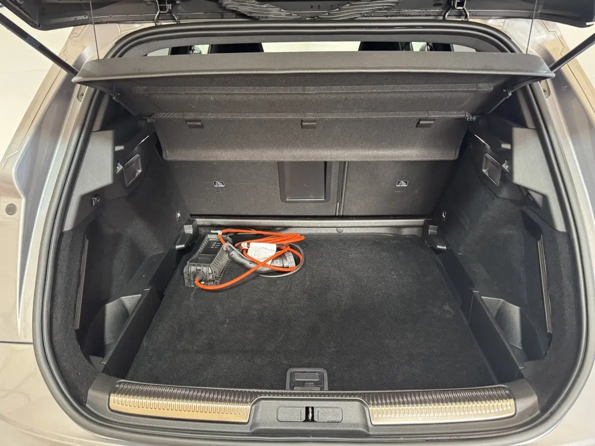 Coffre ouvert vu de l'arrière d'un DS7 Crossback gris foncé avec câble de recharge hybride visible à l'intérieur.