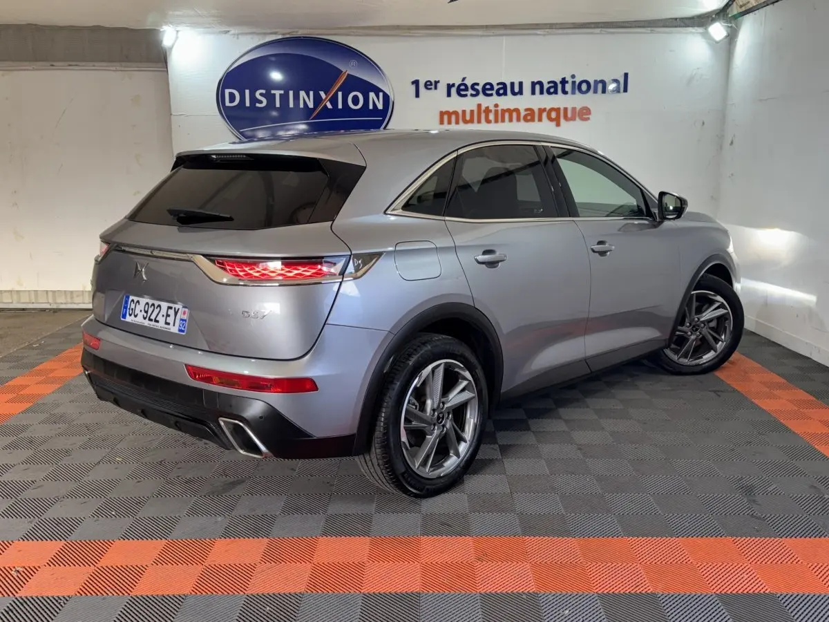 Vue 3/4 arrière droit du DS7 Crossback E-TENSE 225 Bastille+ gris foncé, feux arrière allumés et jantes alliage visibles.