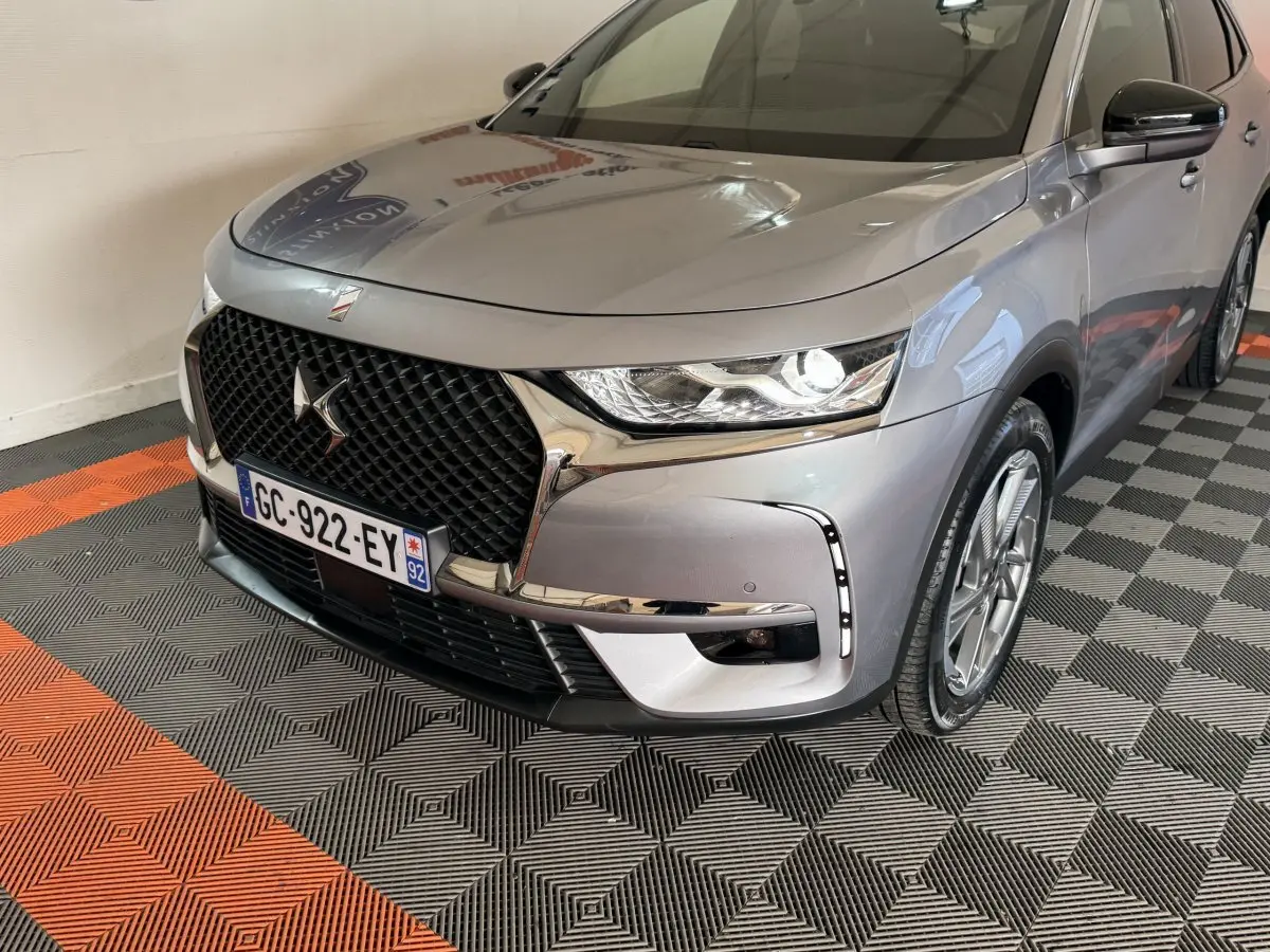 Vue 3/4 avant droit d’un DS7 Crossback E-TENSE gris foncé avec calandre noire et feux LED allumés.