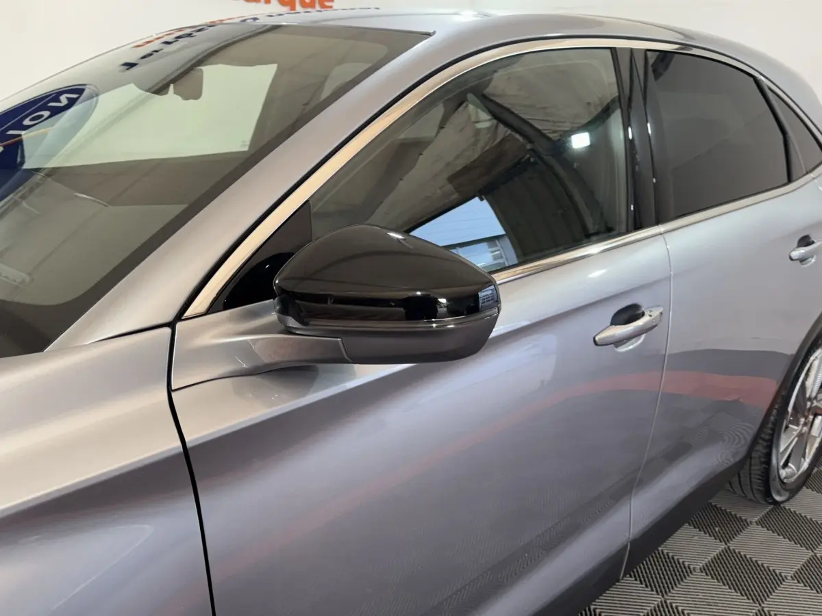 Vue latérale droite du DS7 Crossback gris foncé avec rétroviseur noir brillant et vitres teintées.