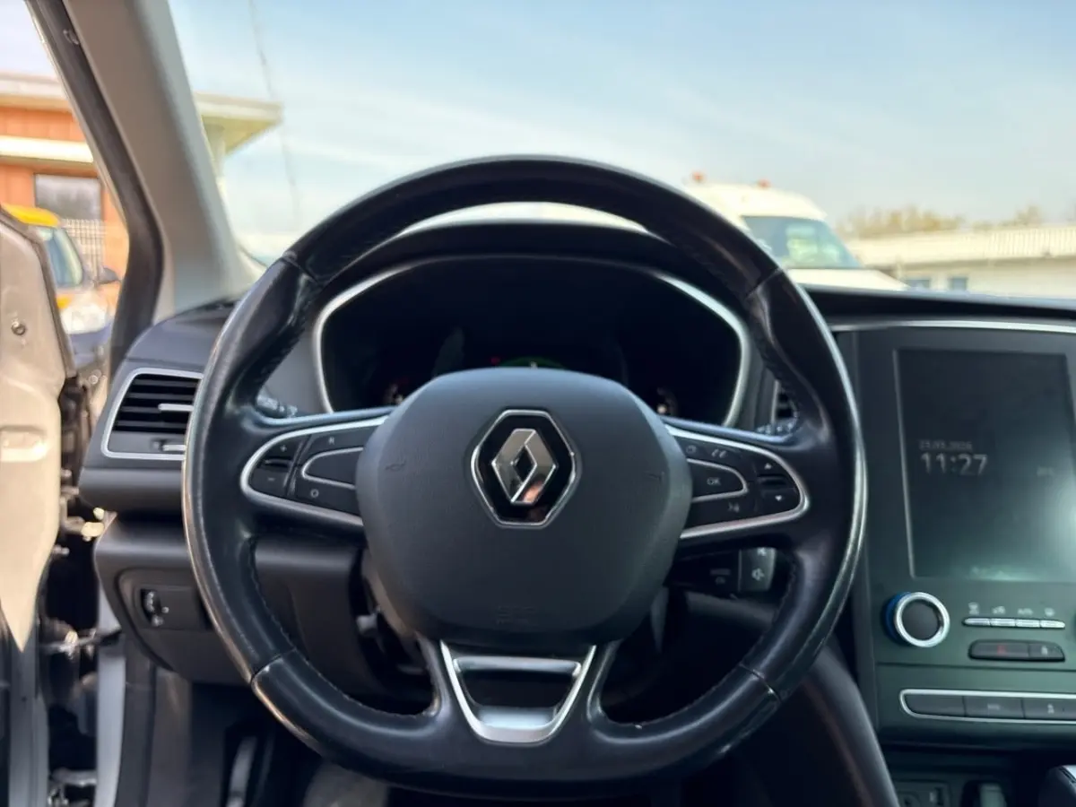 Vue intérieure centrée sur le volant cuir noir de la Renault Mégane Intens, avec écran tactile et tableau de bord visibles.