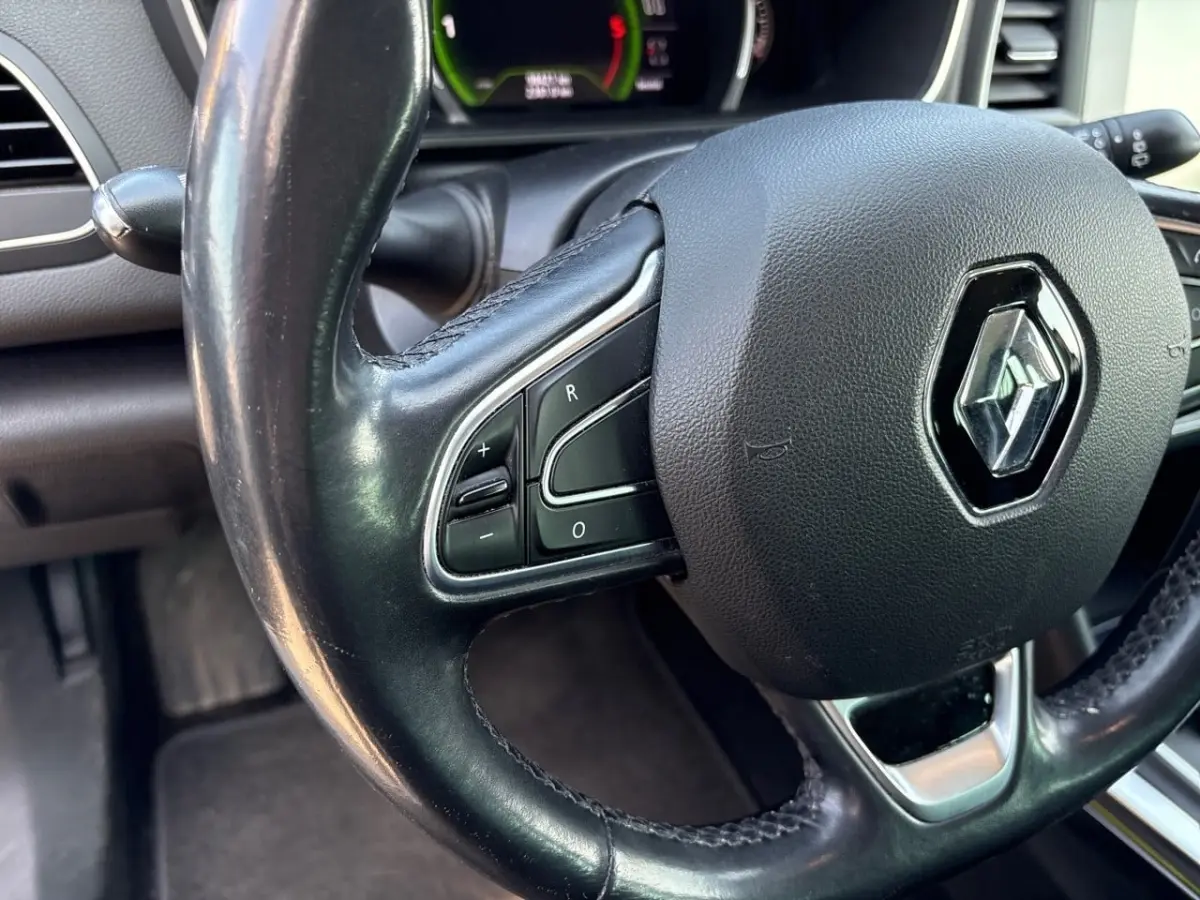 Gros plan sur le volant cuir noir de la Renault Mégane Intens 2020 avec commandes intégrées et logo central brillant.