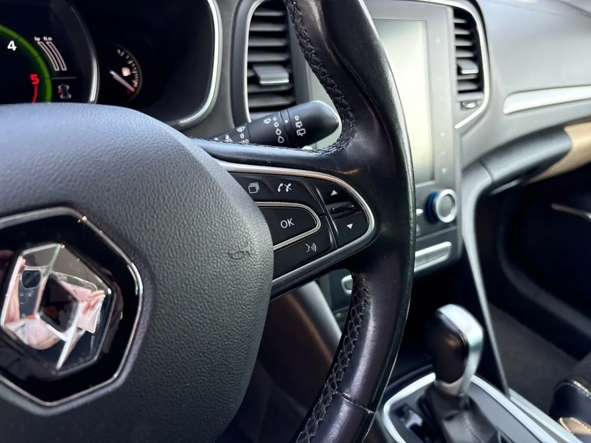 Vue intérieure rapprochée du volant cuir noir et du tableau de bord gris clair d’une Renault Mégane 2020.