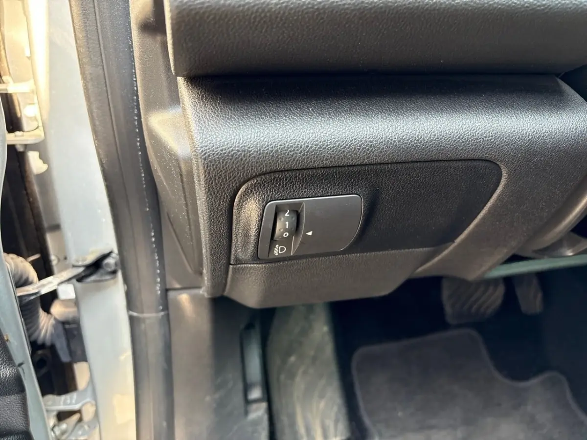 Gros plan sur le réglage des phares situé sous le tableau de bord côté conducteur d’une Renault Mégane 2020 gris clair.