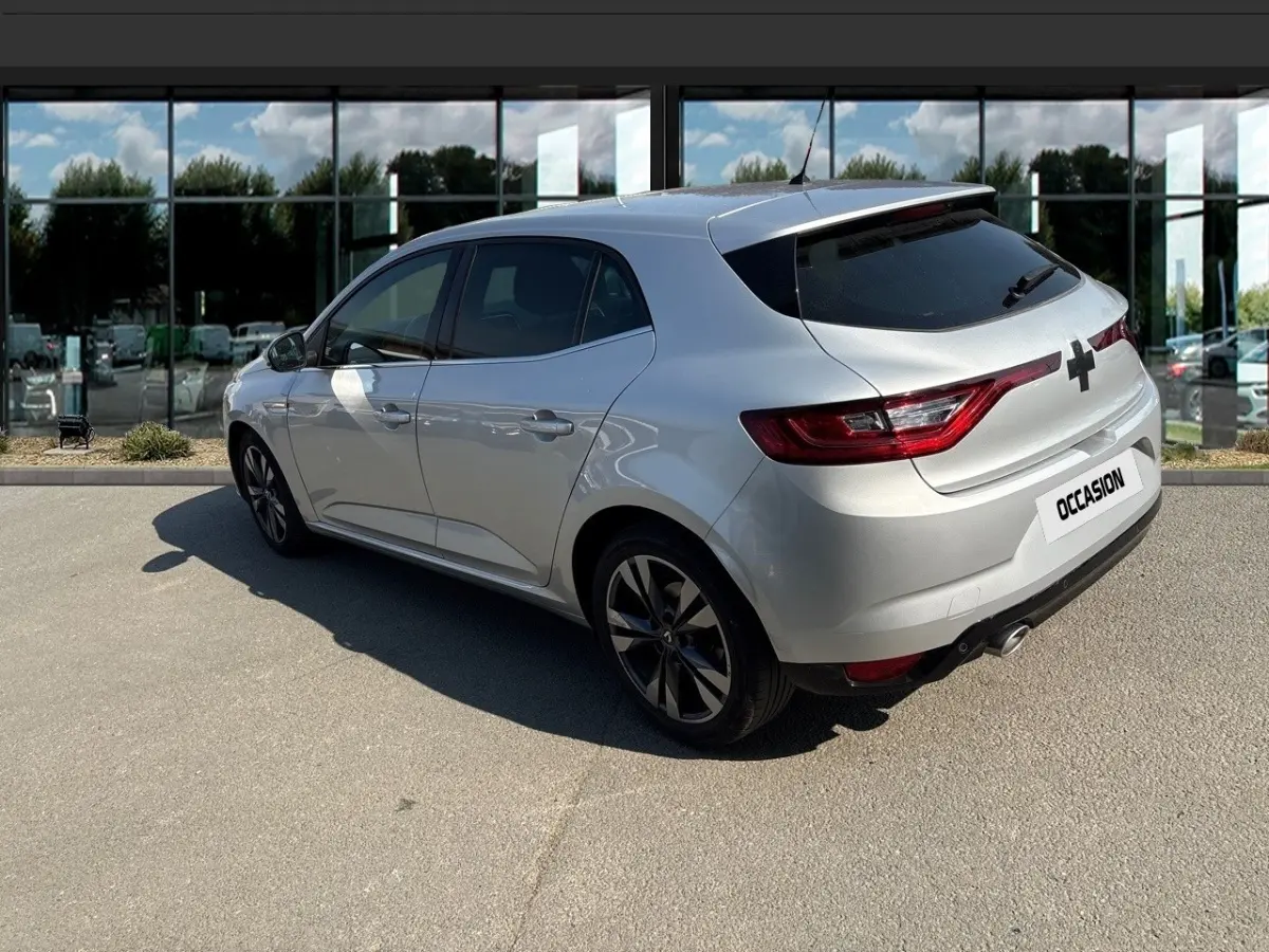 Vue 3/4 arrière droite d'une Renault Mégane Intens bleu dCi 115, couleur argentée, avec jantes noires et vitres teintées.