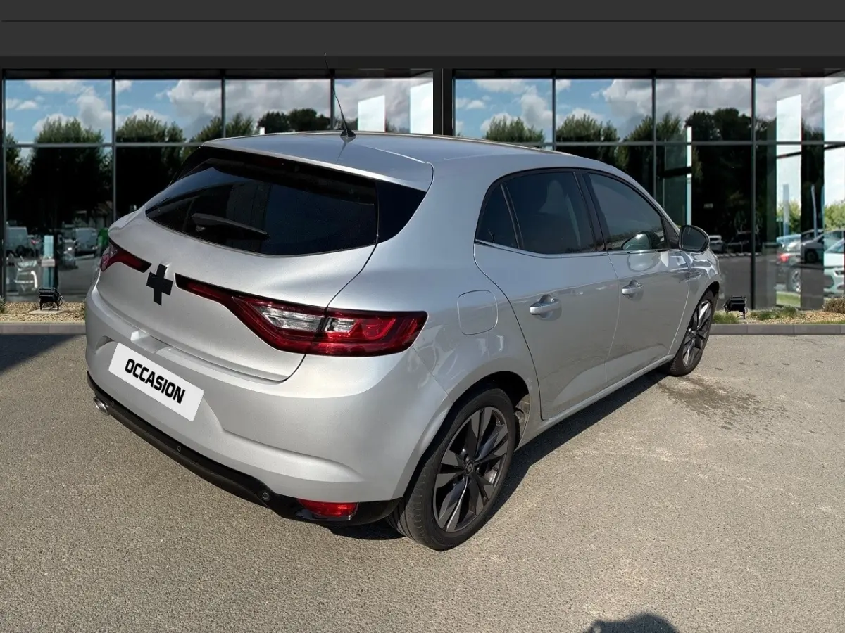 Vue 3/4 arrière droite d'une Renault Mégane Intens Blue dCi 115 gris clair avec jantes alliage et vitres teintées.