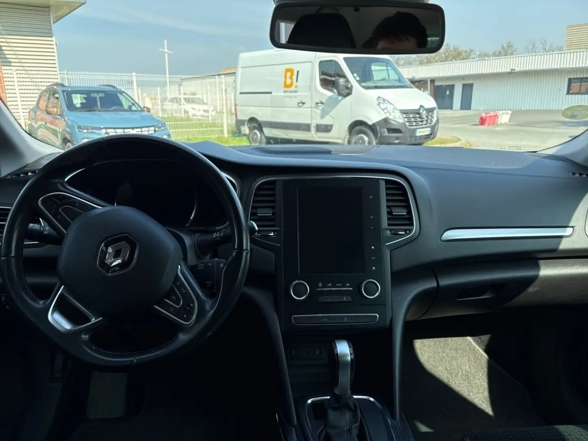 Vue intérieure avant du tableau de bord et volant cuir noir de la Renault Mégane Intens 2020 avec écran tactile central éteint.
