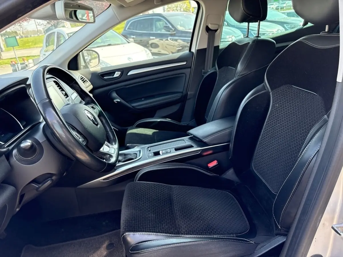 Vue intérieure côté conducteur de la Renault Mégane Intens 2020, sièges noirs avec surpiqûres blanches et volant cuir.