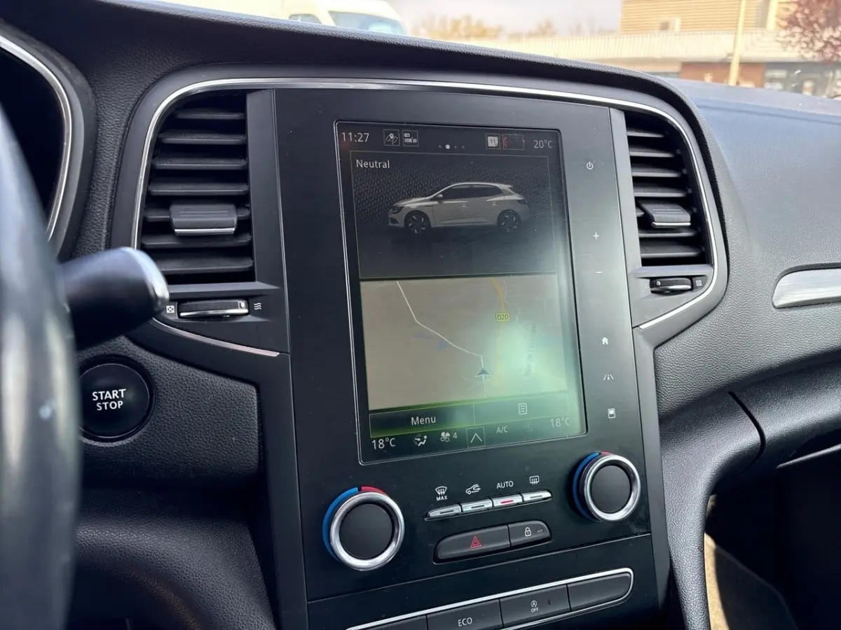 Vue rapprochée du tableau de bord noir de la Renault Mégane Intens avec écran tactile central et bouton Start/Stop visible.