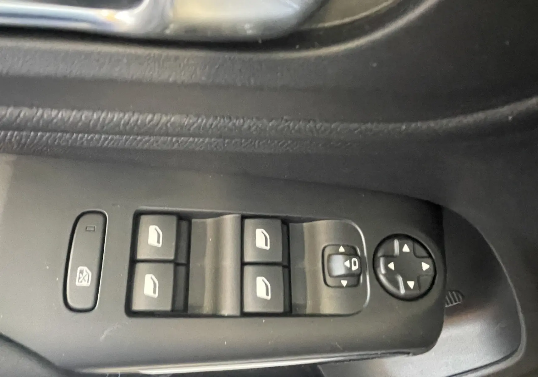 Gros plan sur les commandes de lève-vitres et réglage des rétroviseurs côté conducteur d'une Citroën C5 Aircross bleu foncé.