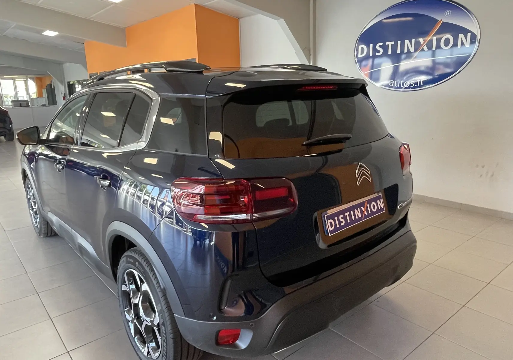 Vue 3/4 arrière droite du Citroën C5 Aircross hybride 2025 en bleu foncé avec jantes alliage biton et vitres surteintées.