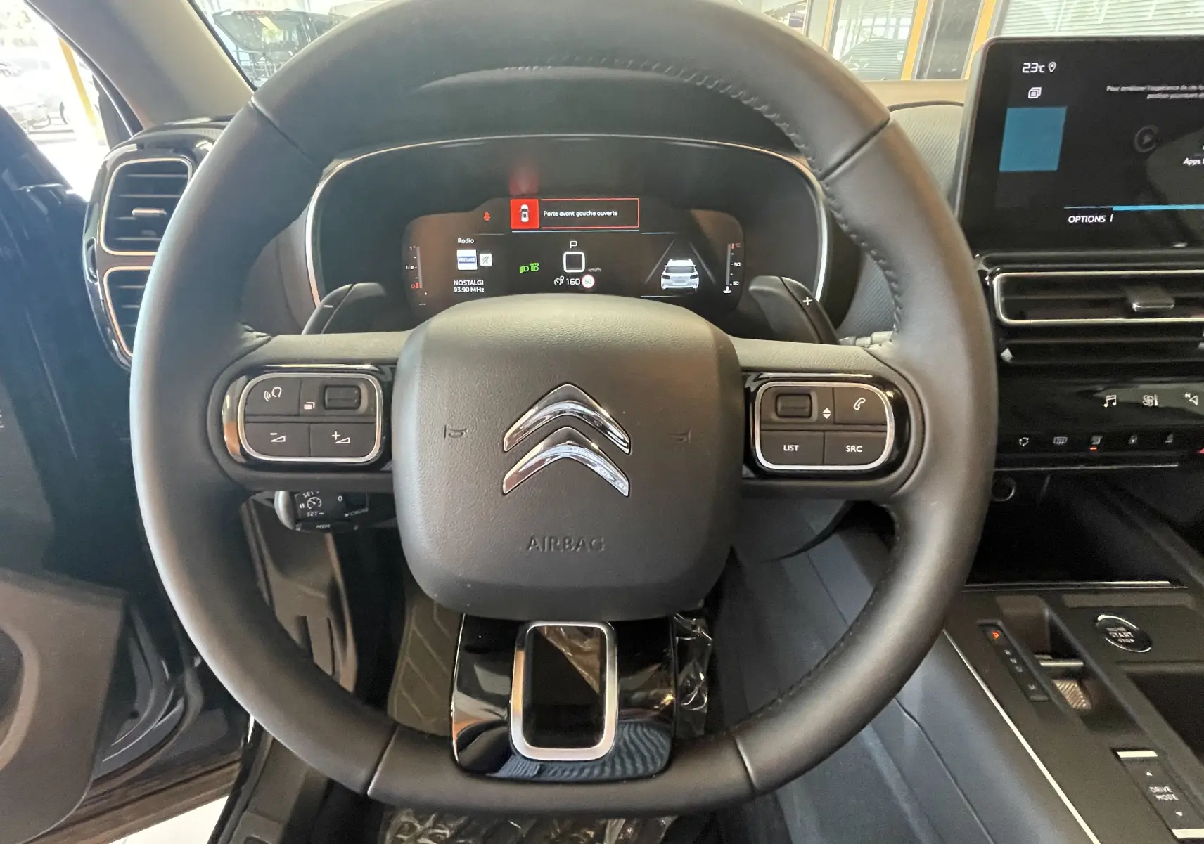 Vue intérieure centrée sur le volant cuir noir du Citroën C5 Aircross hybride 2025, avec tableau de bord digital et écran tactile.