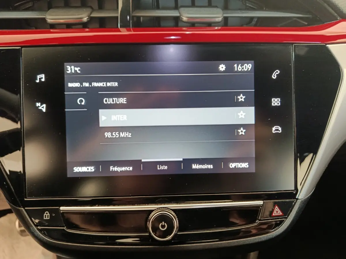 Écran tactile central de l’Opel Corsa rouge 2023 affichant la radio FM avec interface moderne et commandes tactiles.