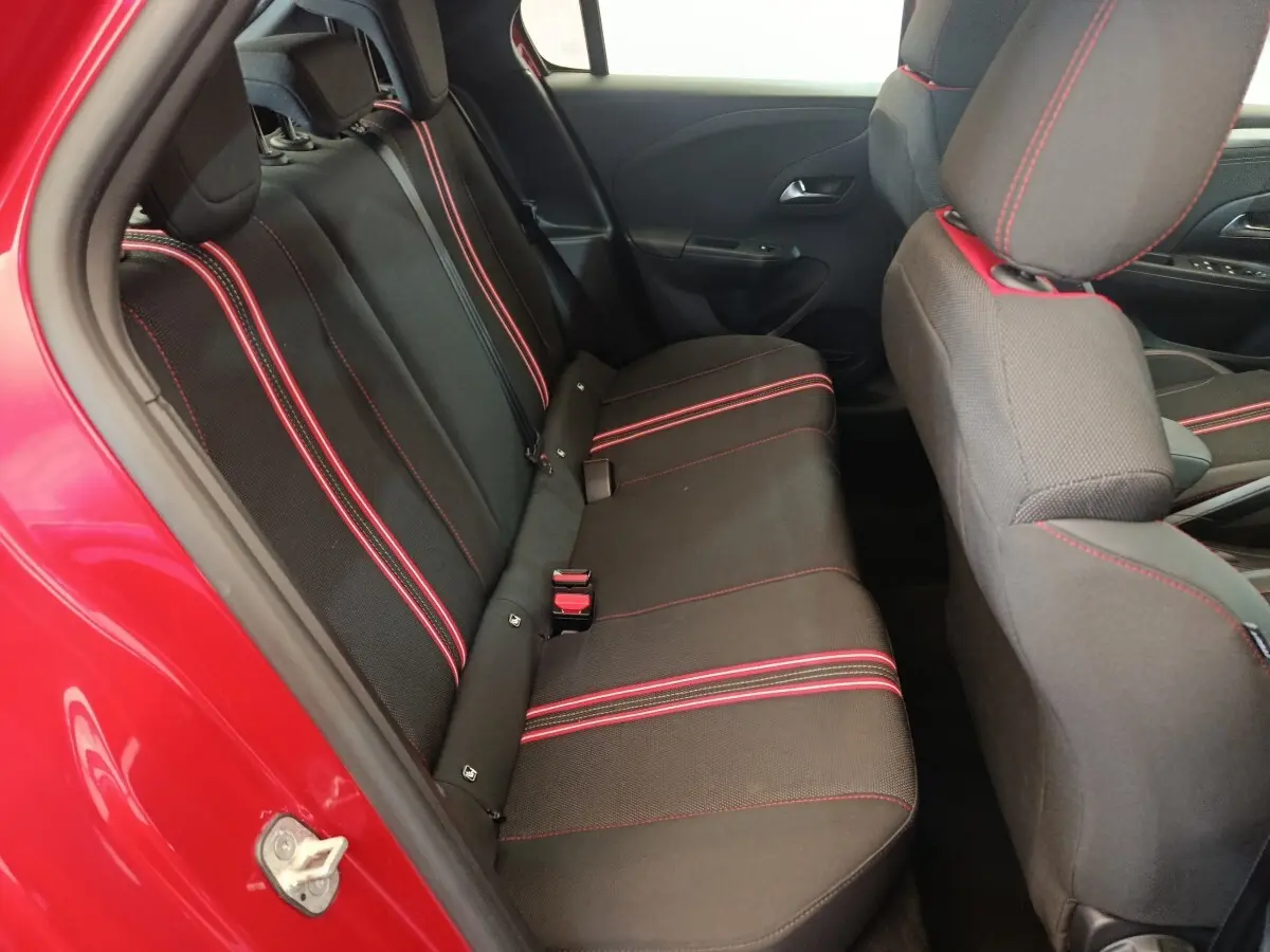 Vue intérieure côté gauche sur la banquette arrière noire avec surpiqûres rouges d'une Opel Corsa rouge 2023.
