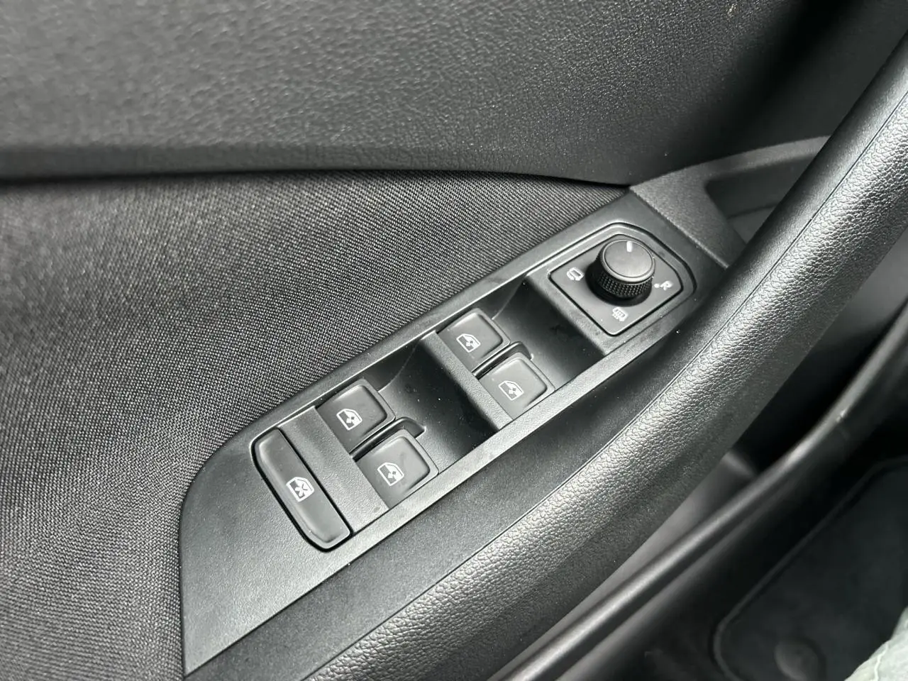 Gros plan sur les commandes de lève-vitres et rétroviseurs côté conducteur du Skoda Kamiq noir Magic 2025.