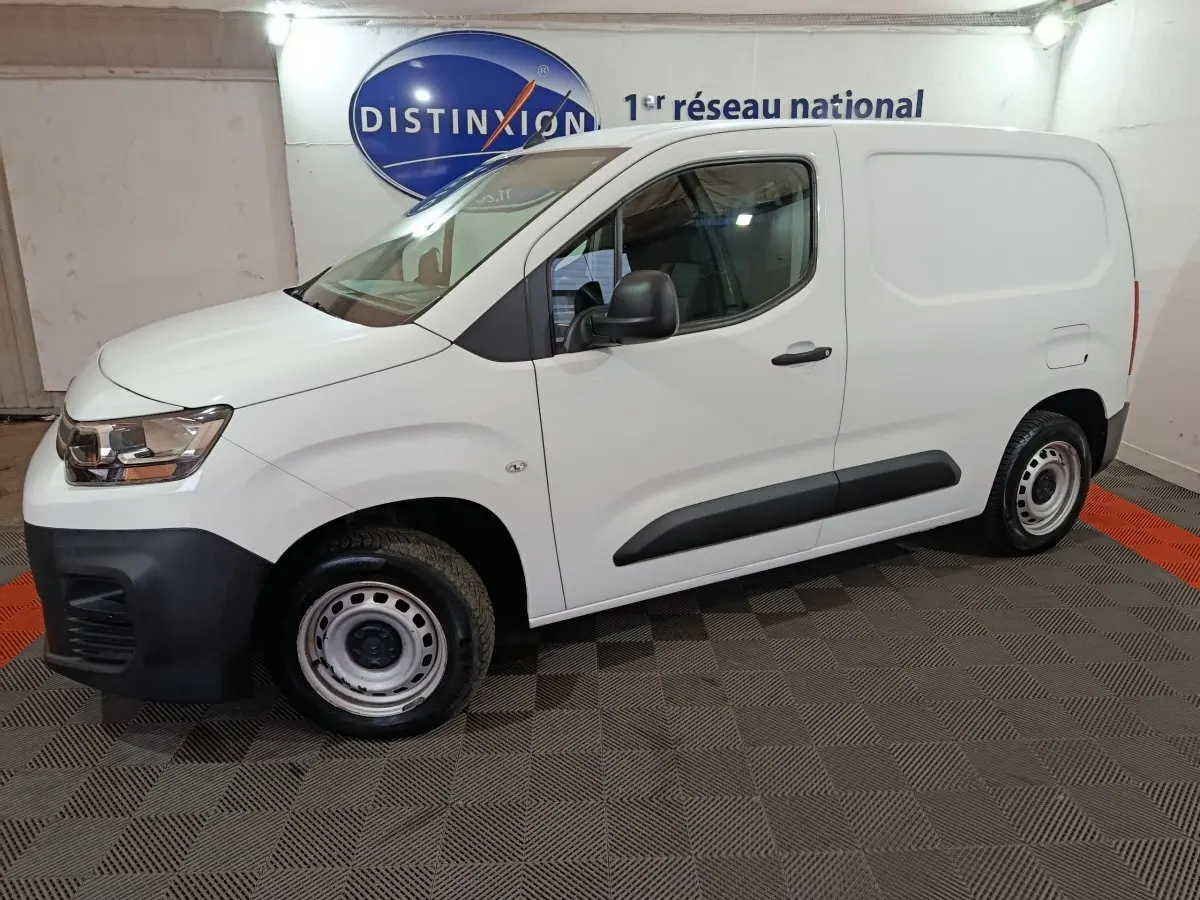 Vue de profil côté gauche d'un utilitaire Citroën Berlingo blanc avec jantes acier et protections noires sur les portes.