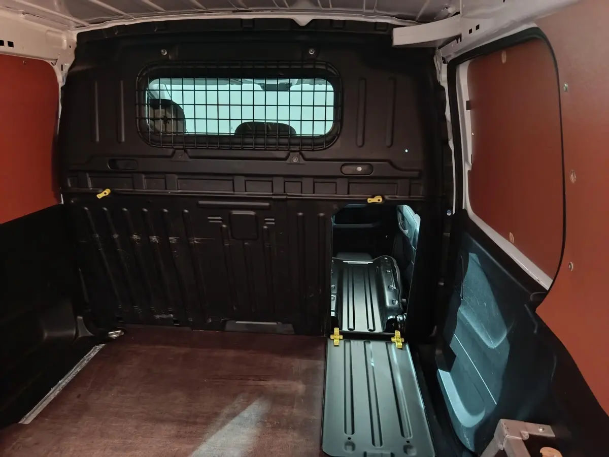 Intérieur du coffre du Citroën Berlingo blanc 2021, cloison pleine noire avec ouverture vers l'avant du véhicule.