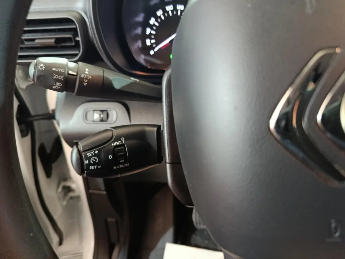 Gros plan sur le volant et les commandes de régulateur de vitesse du Citroën Berlingo blanc, version 2021.