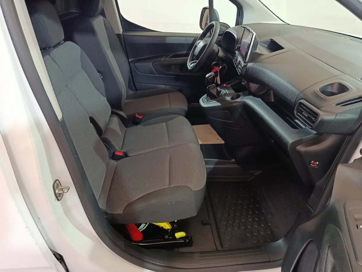 Vue intérieure côté conducteur du Citroën Berlingo blanc 2021, montrant sièges avant gris et tableau de bord noir.