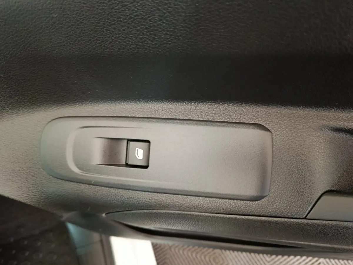 Bouton de commande de lève-vitre noir sur la porte intérieure d'un Citroën Berlingo blanc 2021.