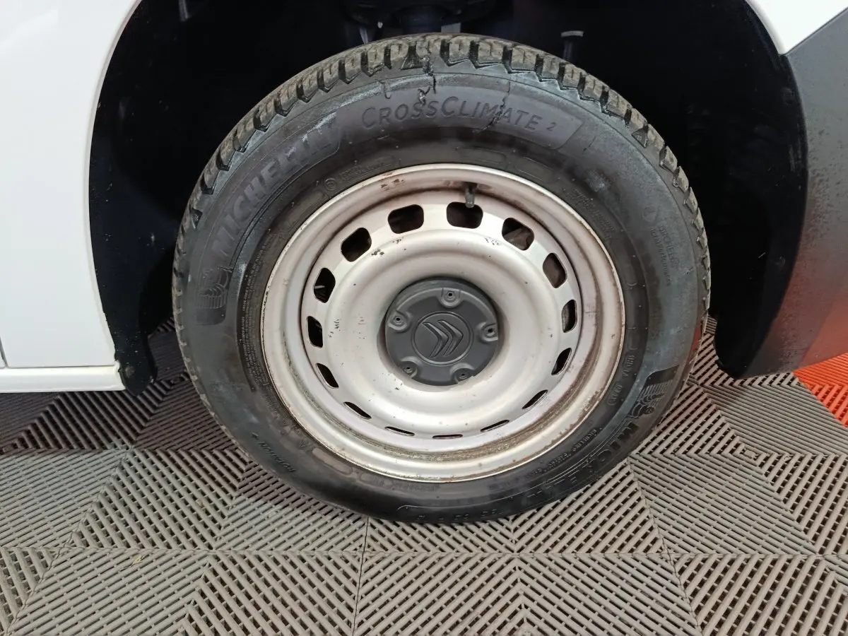 Gros plan sur la roue avant gauche blanche en acier d'un Citroën Berlingo blanc 2021, pneu Michelin CrossClimate.