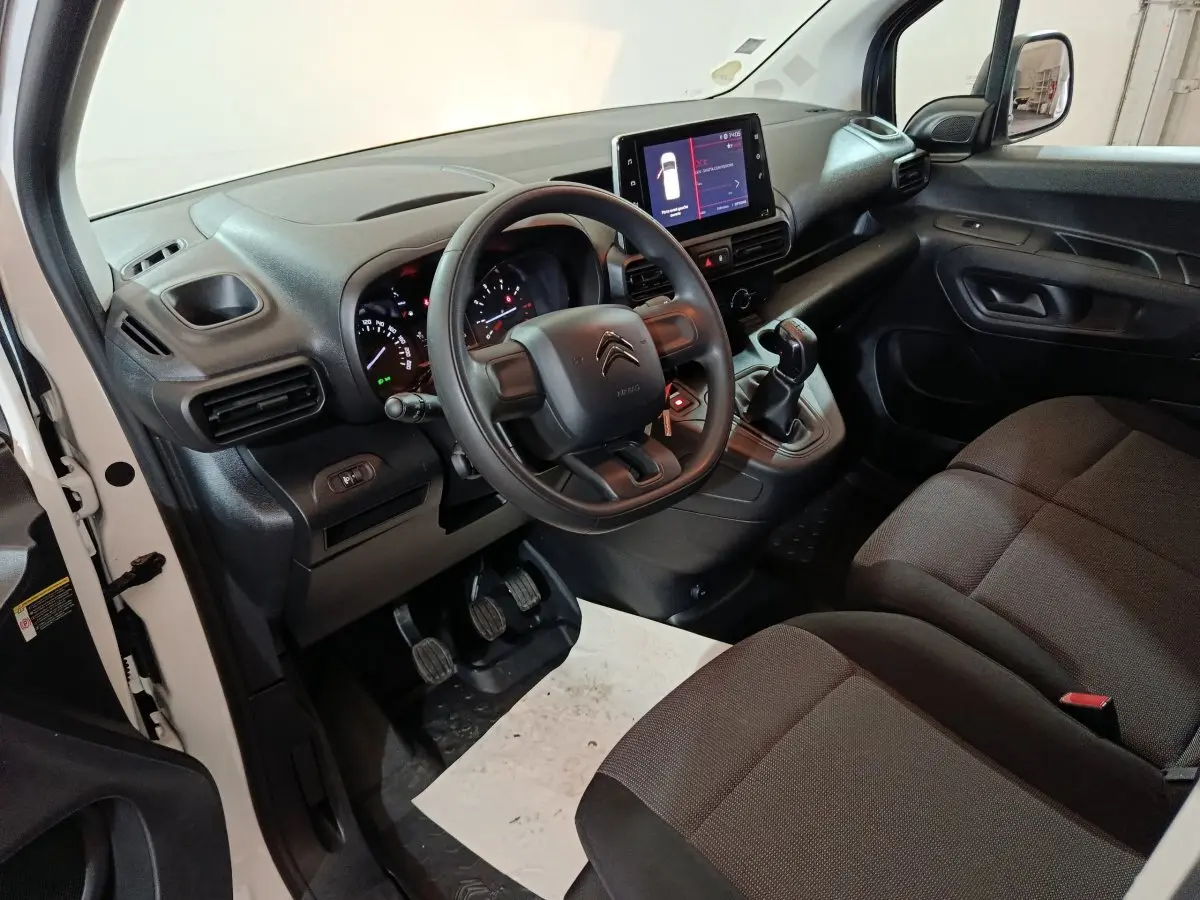 Intérieur du Citroën Berlingo blanc 2021, vue côté conducteur, tableau de bord avec écran tactile et volant noir.