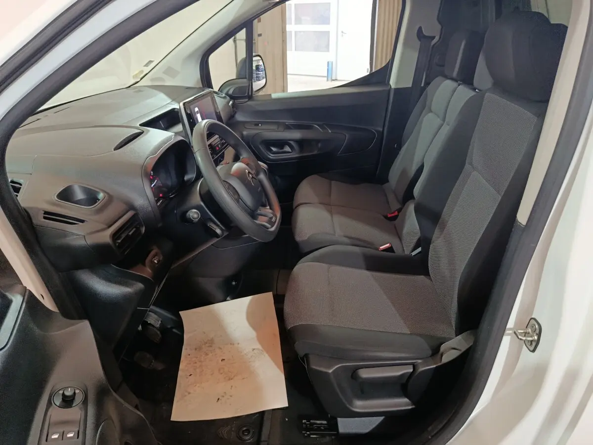 Intérieur du Citroën Berlingo blanc 2021, vue côté conducteur montrant tableau de bord et sièges tissu gris.