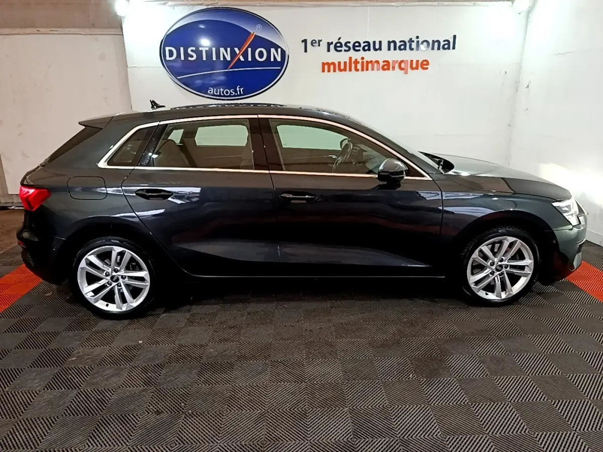 Vue latérale droite d'une Audi A3 35 TFSI gris foncé stationnée en intérieur avec jantes alliage et vitres teintées.