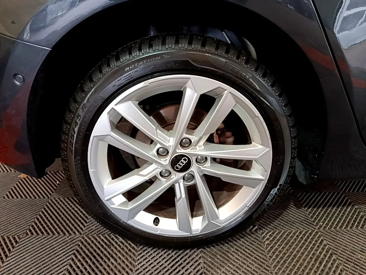 Gros plan sur la roue avant droite d'une Audi A3 gris foncé, mettant en valeur la jante alliage à cinq doubles branches.