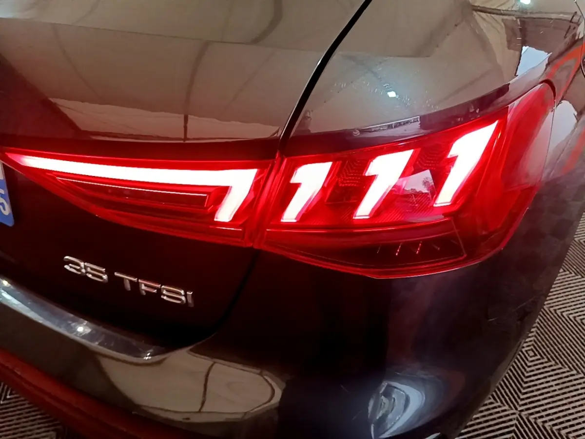 Gros plan sur le feu arrière droit rouge et l’inscription 35 TFSI d’une Audi A3 gris foncé.