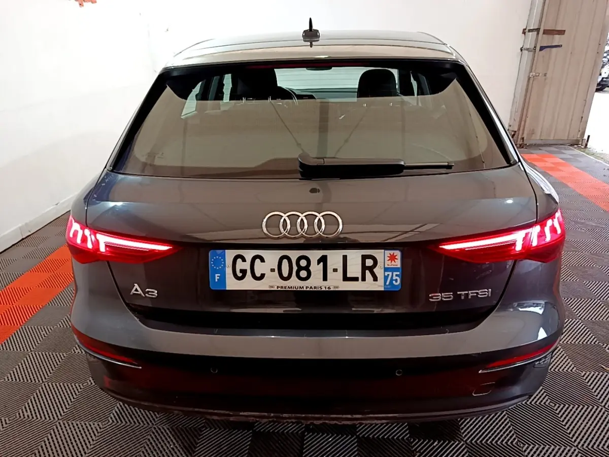 Vue arrière d'une Audi A3 35 TFSI gris foncé avec feux LED allumés dans un garage fermé.