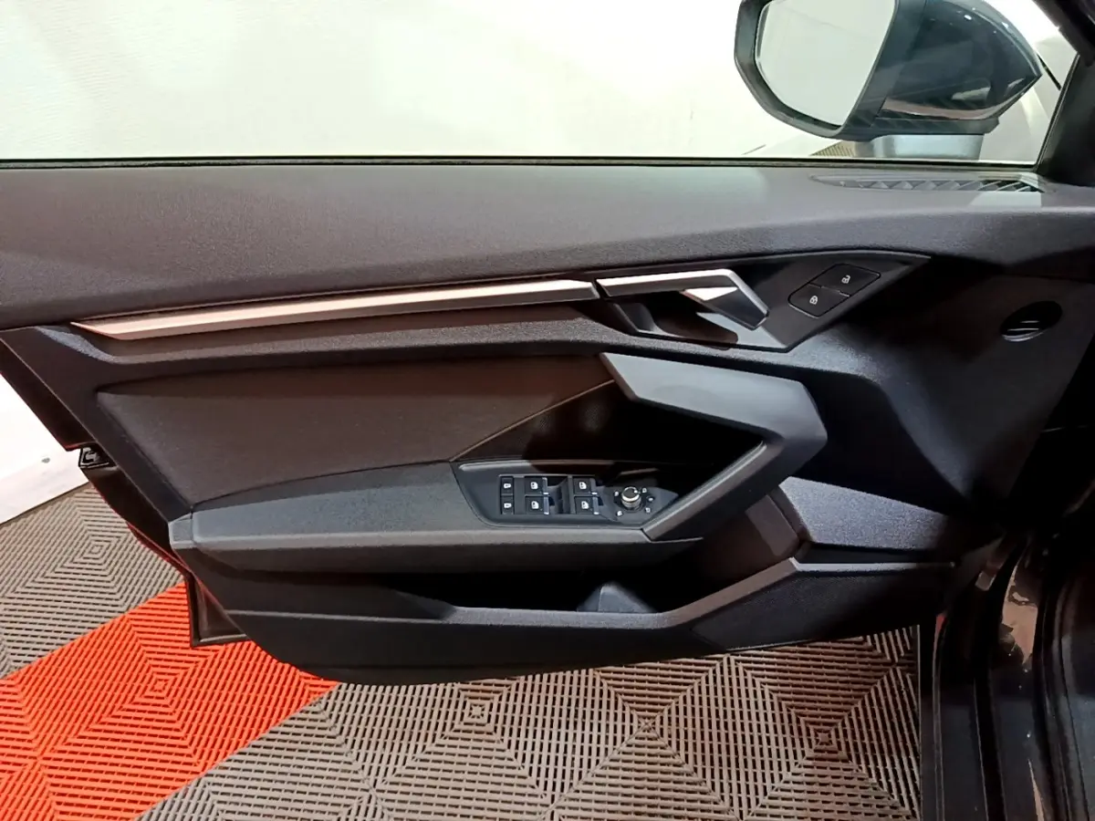 Vue intérieure côté conducteur de la porte noire de l'Audi A3 35 TFSI 2021 avec commandes électriques et poignée argentée.
