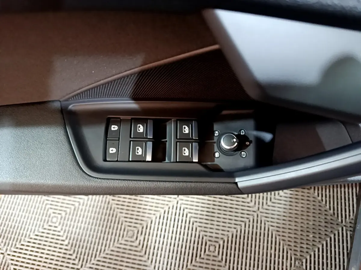 Vue rapprochée des commandes des vitres et rétroviseurs sur la porte côté conducteur d'une Audi A3 gris foncé 2021.