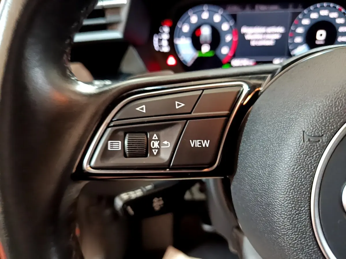 Gros plan sur les commandes gauche du volant cuir noir d'une Audi A3 35 TFSI 150 MHEV Business Line 2021.