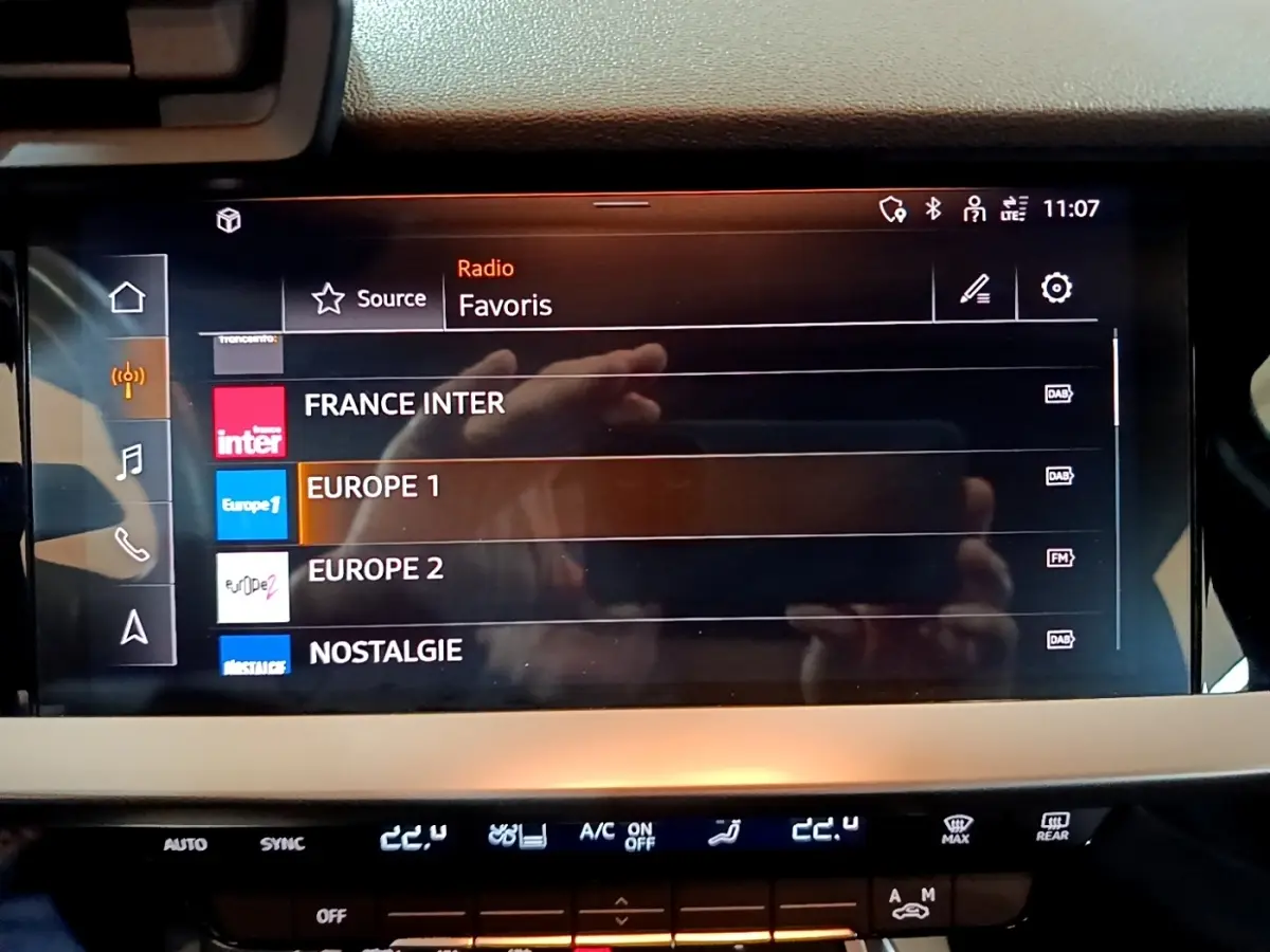 Écran tactile central de l’Audi A3 gris foncé, affichant les stations radio favorites avec interface moderne.