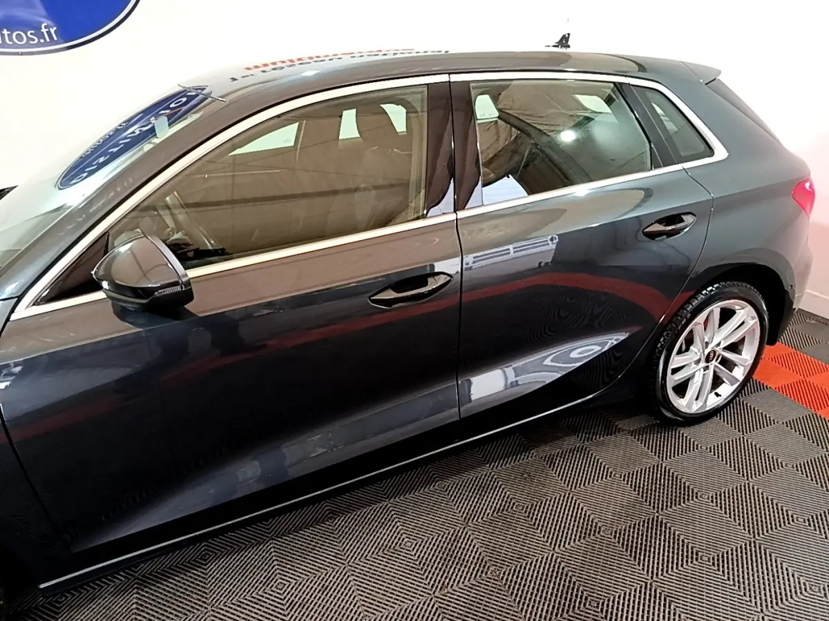 Vue de profil côté gauche d'une Audi A3 gris foncé avec jantes alliage et rétroviseurs noirs brillants.